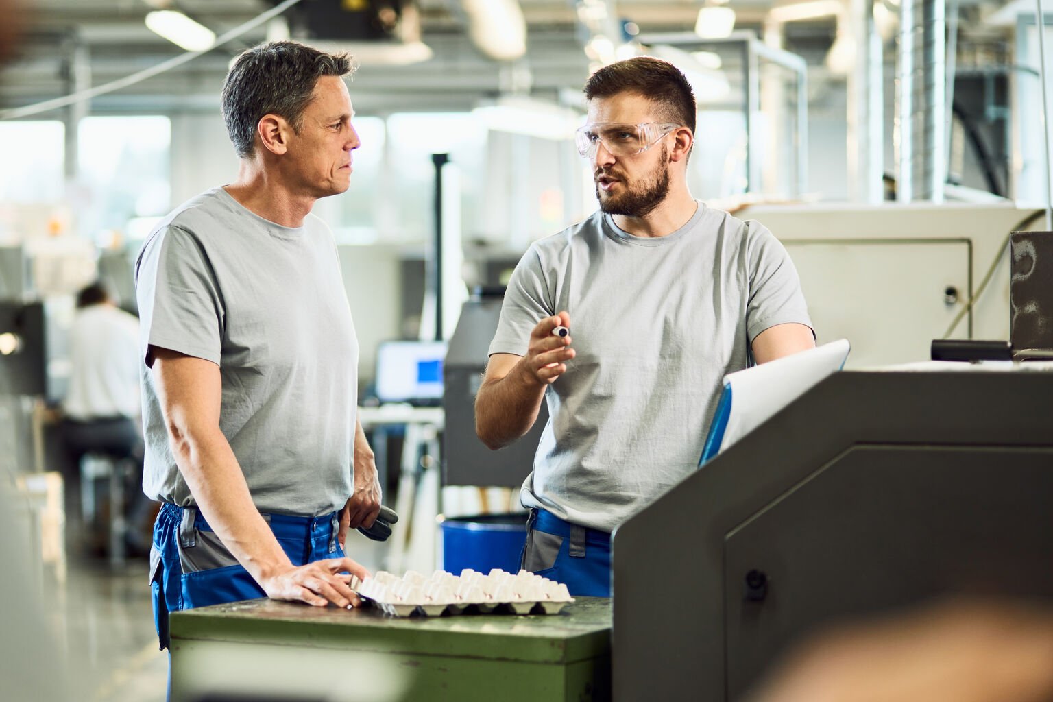 Zwei Facharbeiter stehen an einer Maschine und besprechen die nächsten Arbeitsschritte