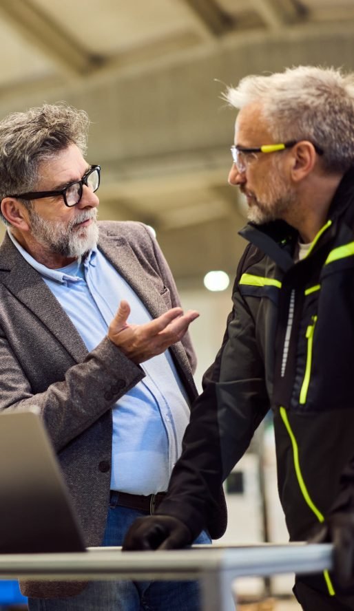 Gespräch am Laptop in der Werkhalle – KI im Mittelstand praktisch eingeordnet